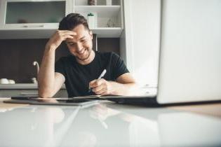 Young man working at laptop with pen. 